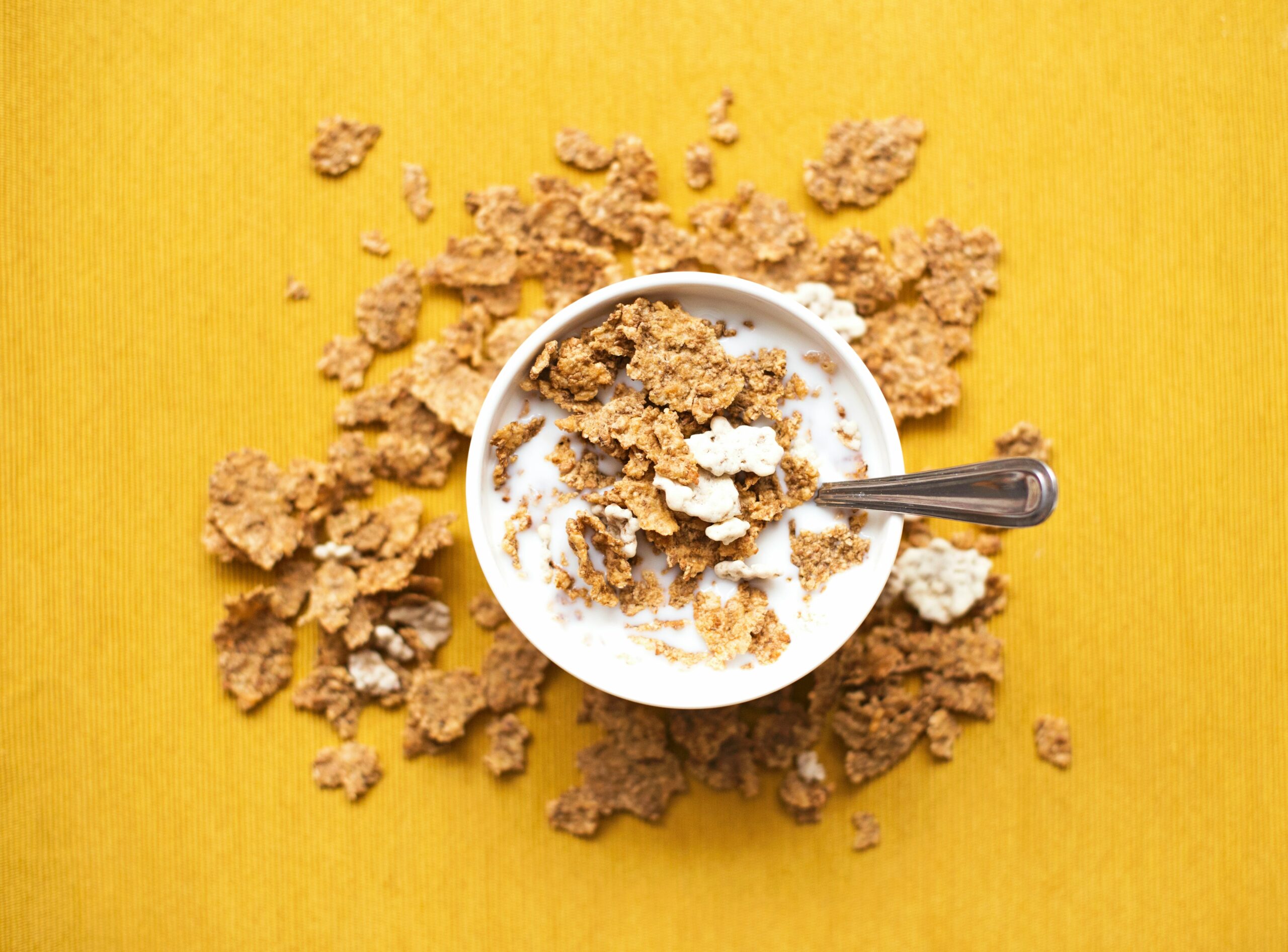 Bowl of cereal with milk on yellow background