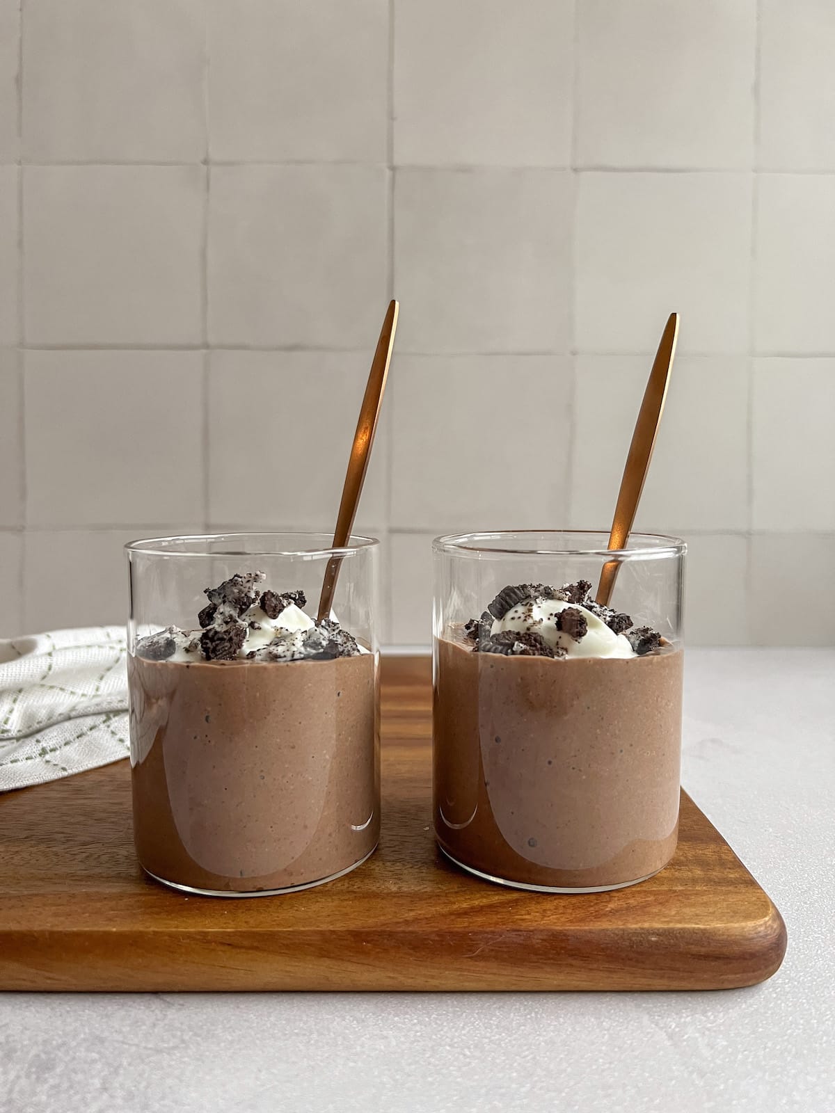 image of two glasses of cottage cheese chocolate mousse on a wood cutting board.