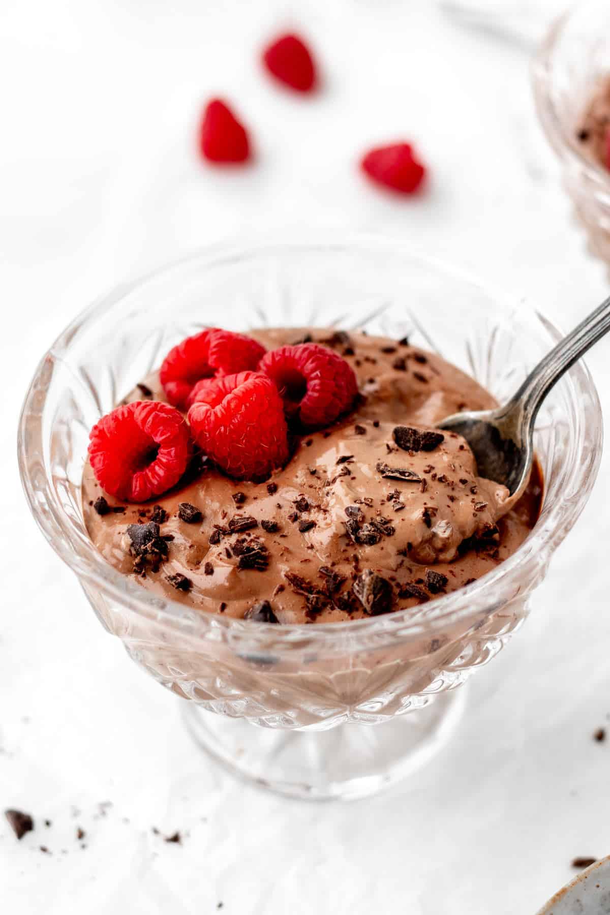 Image of cottage cheese chocolate pudding in a glass dish with raspberries and chocolate shavings on top
